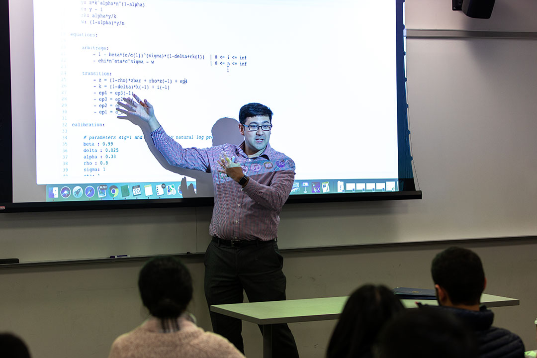 Economics professor demonstrating equations on a projector