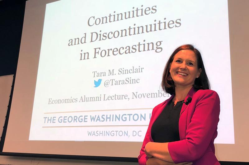 Tara Sinclair in a suit presenting "Continuities and Discontinuities in Forecasting"