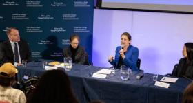 Tara Sinclair speaking on a panel stage alongside CCAS Dean Wahlbeck and two faculty members